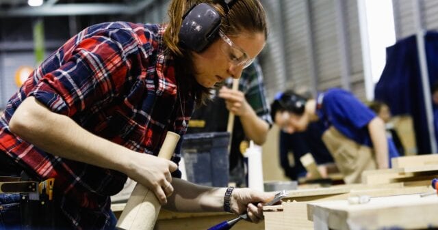 Woman wearing safety goggles and ear plugs, working on a construction project