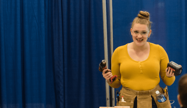 A woman presenting and demonstrating different tools in front of an audience.